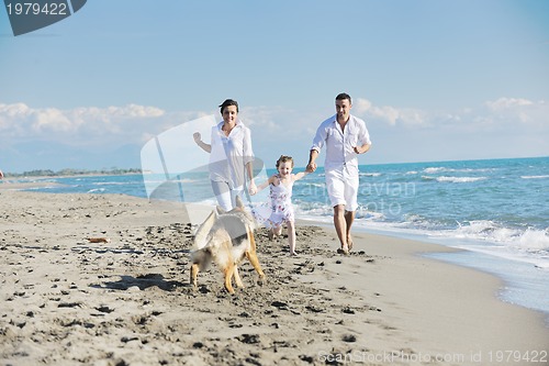 Image of happy family playing with dog on beach