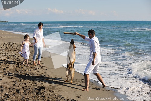 Image of happy family playing with dog on beach