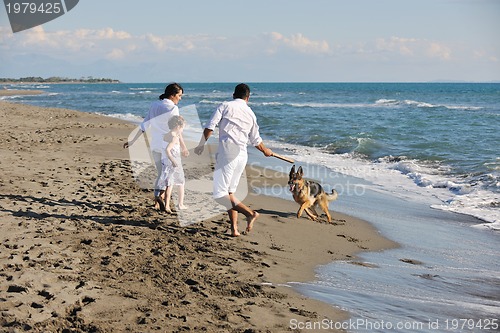Image of happy family playing with dog on beach