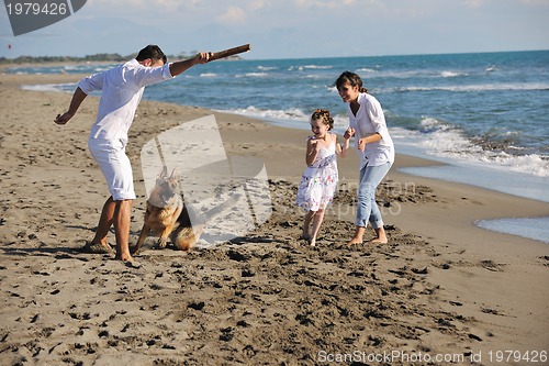 Image of happy family playing with dog on beach