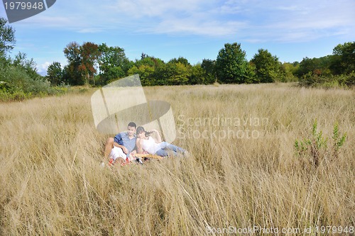 Image of happy couple enjoying countryside picnic in long grass