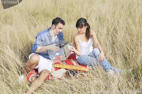 Image of happy couple enjoying countryside picnic in long grass