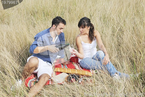 Image of happy couple enjoying countryside picnic in long grass