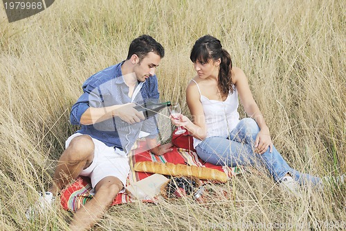 Image of happy couple enjoying countryside picnic in long grass