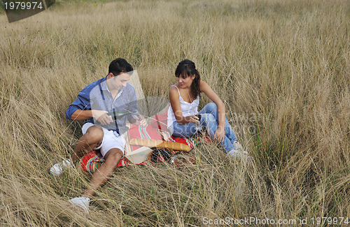 Image of happy couple enjoying countryside picnic in long grass