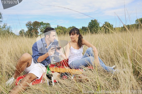 Image of happy couple enjoying countryside picnic in long grass