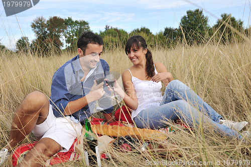 Image of happy couple enjoying countryside picnic in long grass