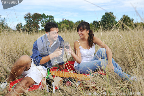 Image of happy couple enjoying countryside picnic in long grass