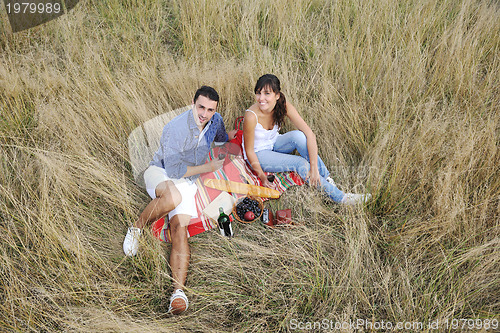 Image of happy couple enjoying countryside picnic in long grass