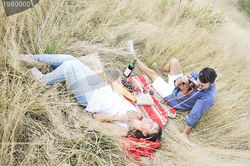 Image of happy couple enjoying countryside picnic in long grass