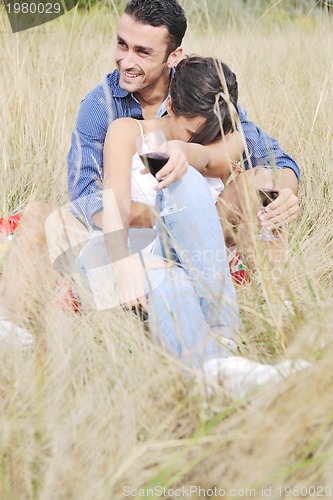 Image of happy couple enjoying countryside picnic in long grass