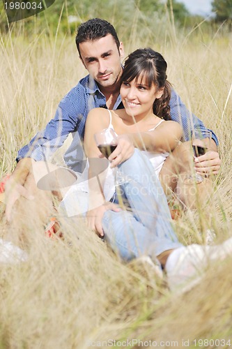 Image of happy couple enjoying countryside picnic in long grass
