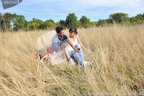 Image of happy couple enjoying countryside picnic in long grass