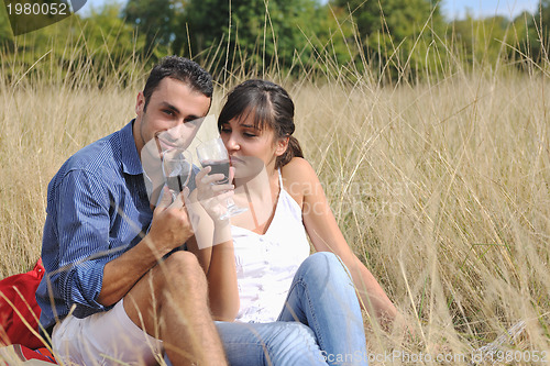 Image of happy couple enjoying countryside picnic in long grass