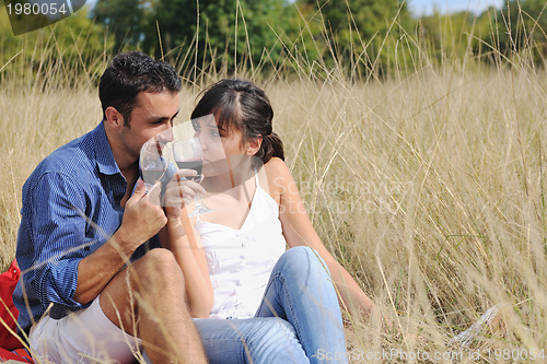 Image of happy couple enjoying countryside picnic in long grass