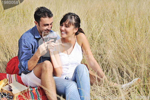 Image of happy couple enjoying countryside picnic in long grass