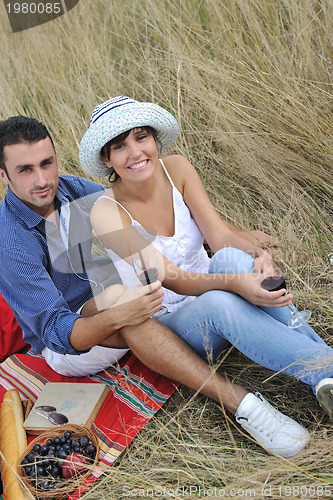 Image of happy couple enjoying countryside picnic in long grass