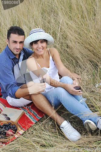 Image of happy couple enjoying countryside picnic in long grass