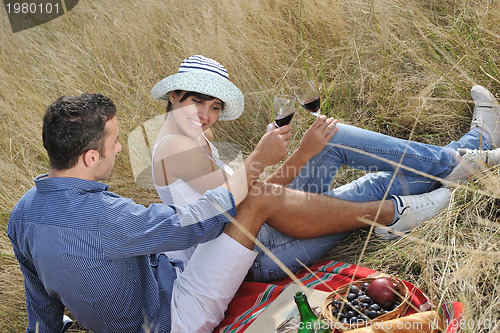 Image of happy couple enjoying countryside picnic in long grass