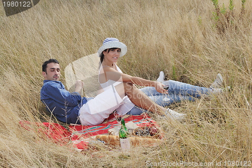 Image of happy couple enjoying countryside picnic in long grass