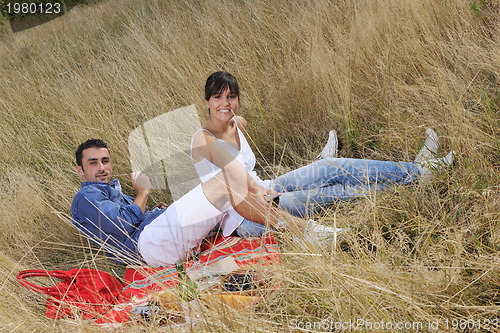 Image of happy couple enjoying countryside picnic in long grass