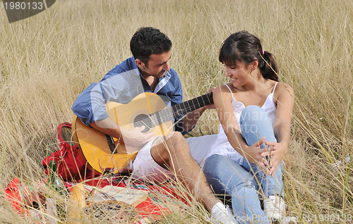 Image of happy couple enjoying countryside picnic in long grass