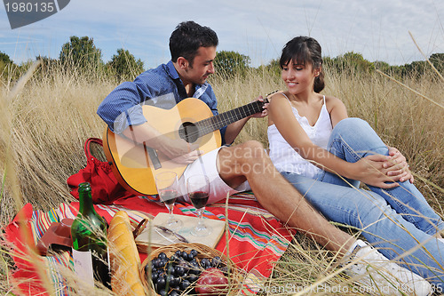 Image of happy couple enjoying countryside picnic in long grass