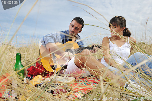 Image of happy couple enjoying countryside picnic in long grass