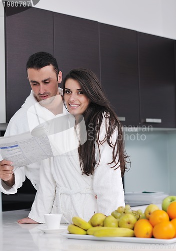Image of Happy couple reading the newspaper in the kitchen at breakfast