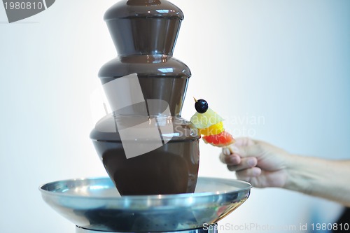 Image of liquid chocolate fountain and fresh fruits on stick