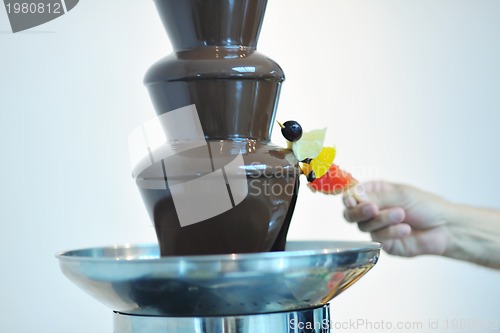 Image of liquid chocolate fountain and fresh fruits on stick