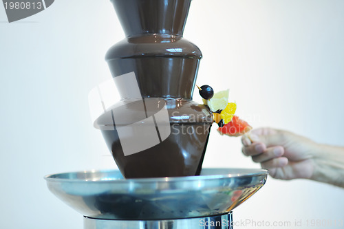 Image of liquid chocolate fountain and fresh fruits on stick