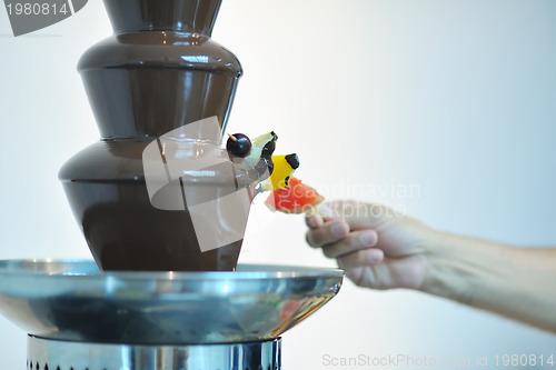Image of liquid chocolate fountain and fresh fruits on stick