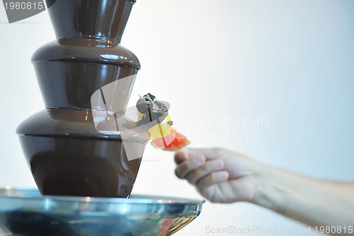 Image of liquid chocolate fountain and fresh fruits on stick