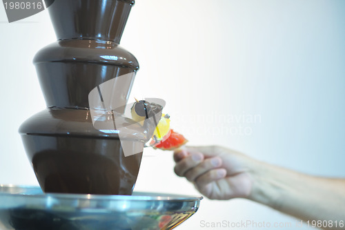 Image of liquid chocolate fountain and fresh fruits on stick