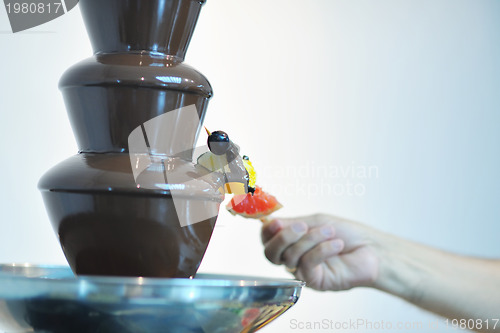 Image of liquid chocolate fountain and fresh fruits on stick