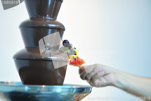 Image of liquid chocolate fountain and fresh fruits on stick