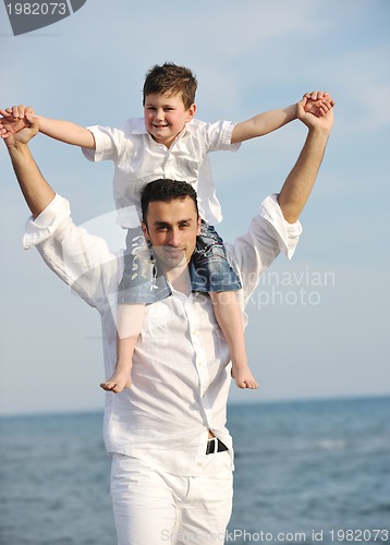Image of happy father and son have fun and enjoy time on beach