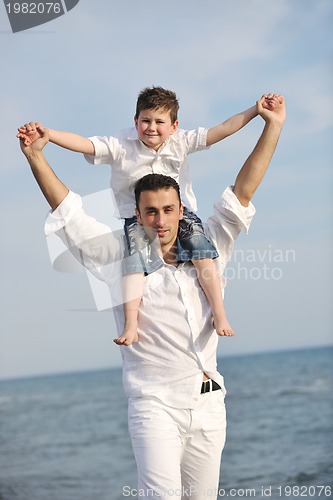 Image of happy father and son have fun and enjoy time on beach