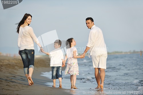 Image of happy young family have fun on beach at sunset
