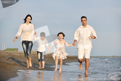 Image of happy young family have fun on beach at sunset