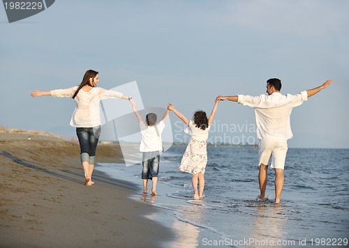 Image of happy young family have fun on beach at sunset