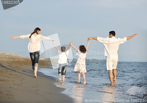 Image of happy young family have fun on beach at sunset