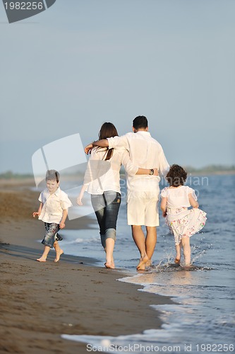 Image of happy young family have fun on beach at sunset