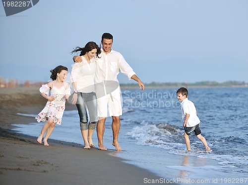 Image of happy young family have fun on beach at sunset