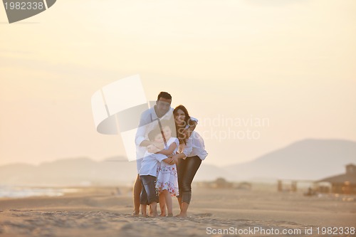 Image of happy young family have fun on beach at sunset