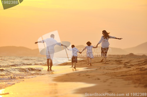 Image of happy young family have fun on beach at sunset