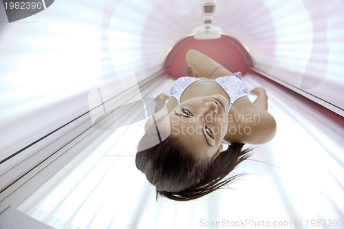 Image of Beautiful young woman tanning in solarium