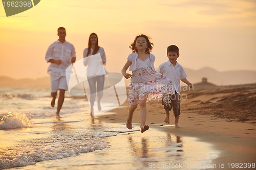 Image of happy young family have fun on beach at sunset