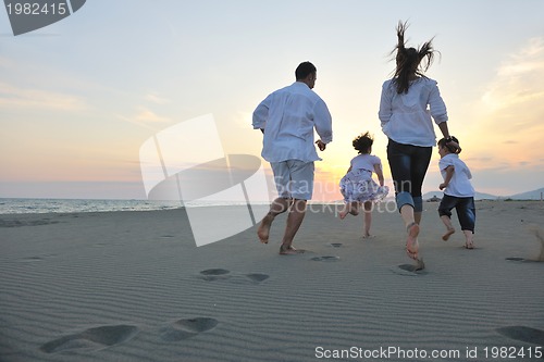 Image of happy young family have fun on beach at sunset